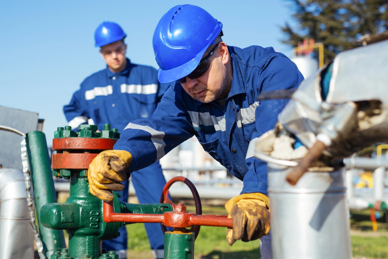Oil and gas worker operating a valve at a facility